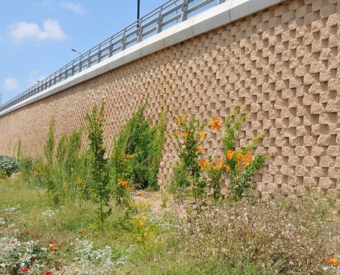 קירות קרקע משוריינת מבלוקי קיסטון בגוון כורכרי.