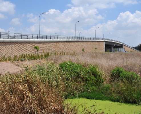 "גשר התל" המוביל אל שמורת אפק, קרית ביאליק . קירות קרקע משוריינת מבלוקי קיסטון בגוון כורכרי. תכנון: מרגלית סוכוי אדריכלות נוף.